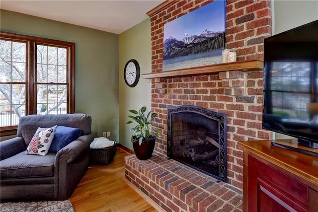 living room featuring baseboards, light wood-style flooring, and a fireplace