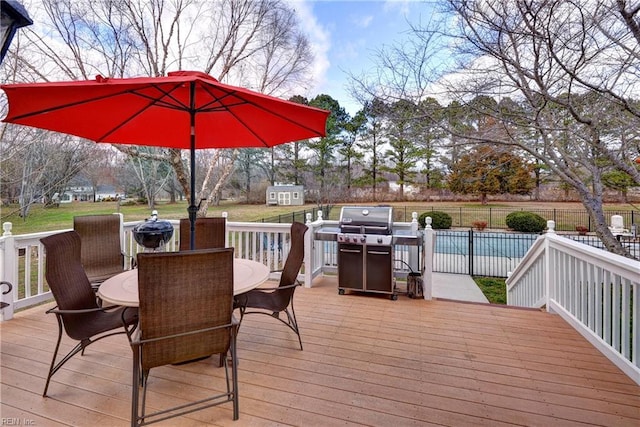 wooden deck with outdoor dining space, area for grilling, a yard, and fence