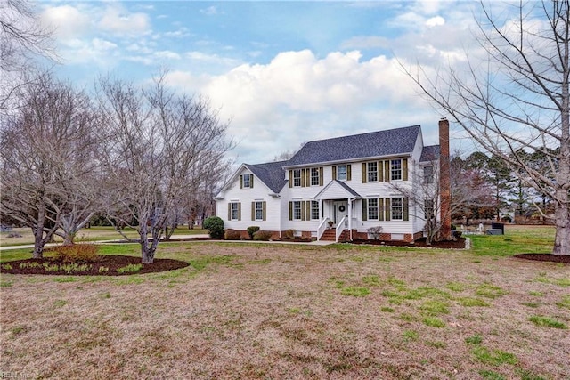 colonial-style house featuring crawl space, a chimney, and a front yard