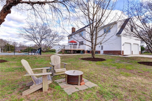 view of yard featuring fence, a fire pit, a wooden deck, a garage, and stairs