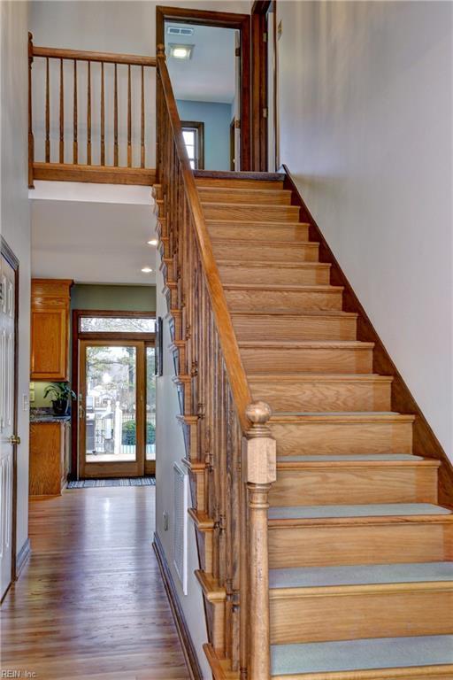 stairway with wood finished floors and a towering ceiling