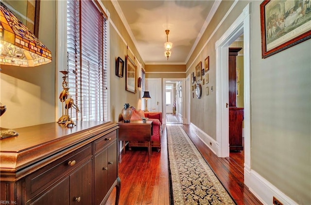 hallway featuring dark wood-style floors, baseboards, and ornamental molding