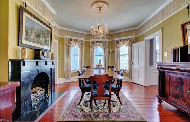 dining area featuring dark wood-style floors, baseboards, a high end fireplace, ornamental molding, and a chandelier