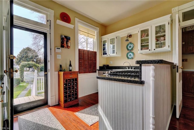 kitchen featuring dark countertops, wood finished floors, and a wainscoted wall