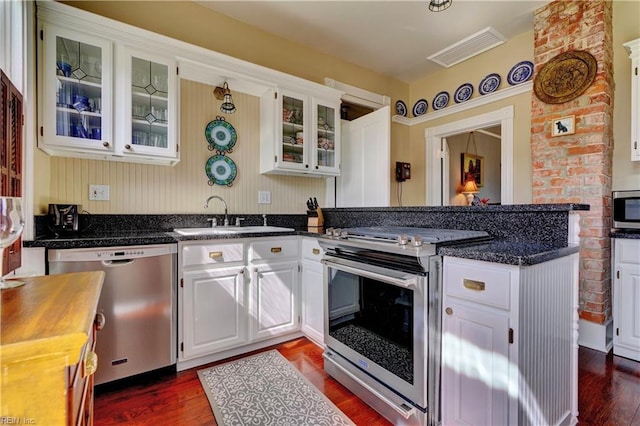 kitchen with visible vents, a sink, appliances with stainless steel finishes, a peninsula, and dark wood-style flooring