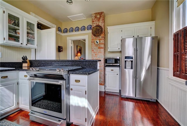 kitchen featuring glass insert cabinets, dark wood finished floors, appliances with stainless steel finishes, a peninsula, and white cabinets