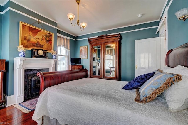 bedroom featuring a premium fireplace, a chandelier, crown molding, and hardwood / wood-style flooring