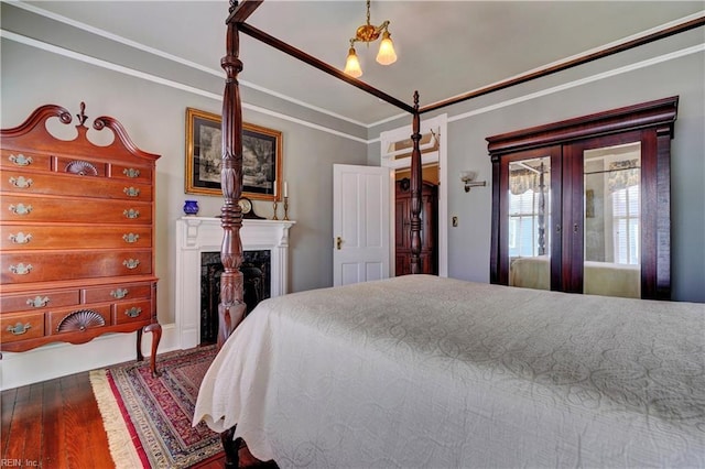 bedroom featuring a fireplace, wood finished floors, and ornamental molding