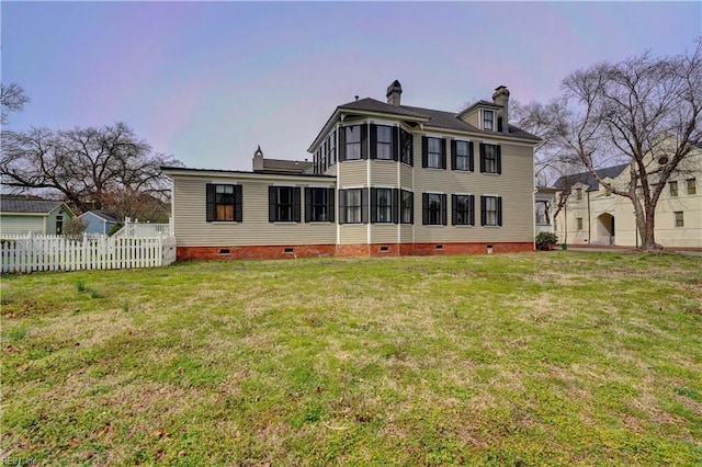 back of property with crawl space, a chimney, a yard, and fence