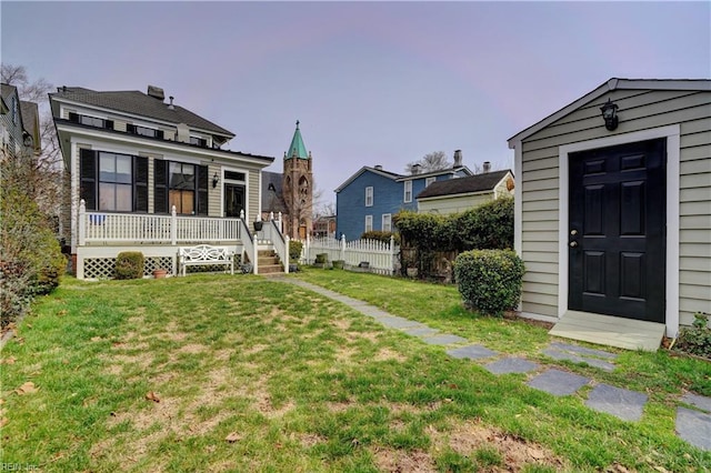 view of yard featuring an outdoor structure, a porch, and fence