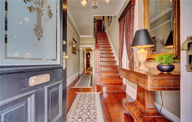 entrance foyer featuring baseboards, wood finished floors, ornamental molding, and stairs