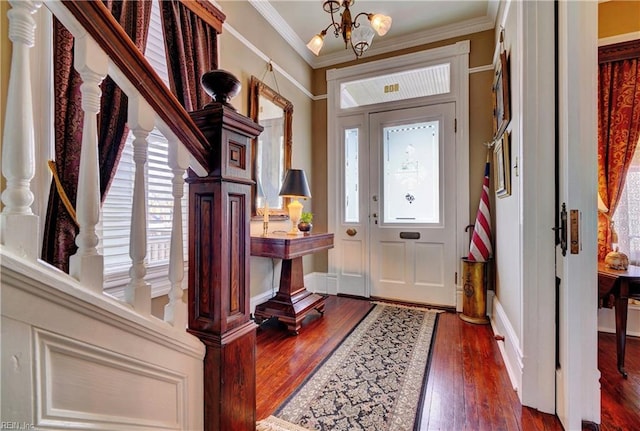 foyer featuring dark wood-type flooring, ornamental molding, an inviting chandelier, baseboards, and stairs