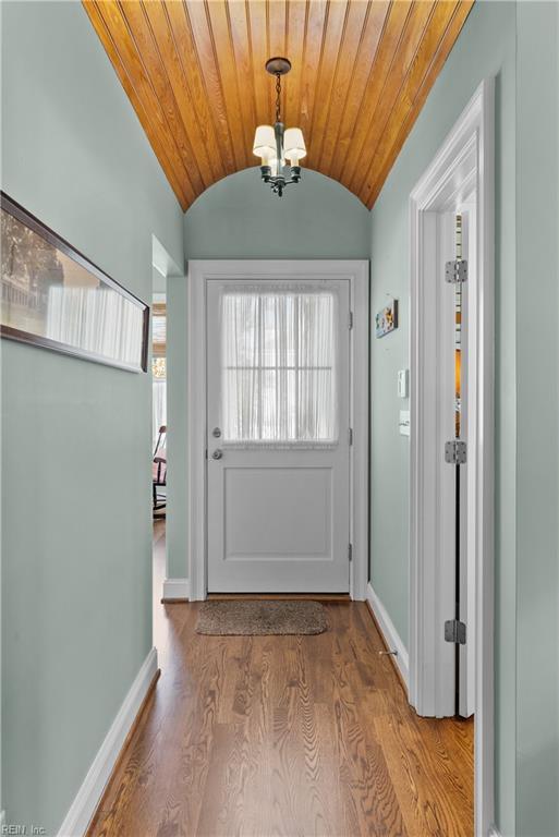 doorway featuring wood ceiling, baseboards, lofted ceiling, and wood finished floors