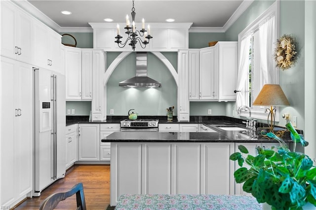 kitchen featuring high end fridge, ornamental molding, a sink, stainless steel gas range oven, and wall chimney exhaust hood