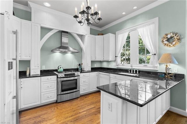 kitchen featuring stainless steel range with gas stovetop, a peninsula, crown molding, and wall chimney range hood