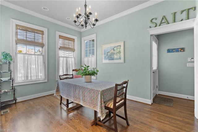 dining area with dark wood-type flooring, baseboards, a chandelier, and ornamental molding