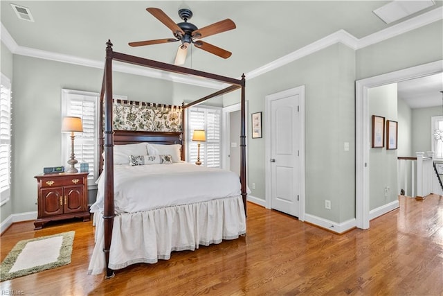 bedroom featuring visible vents, crown molding, baseboards, and wood finished floors