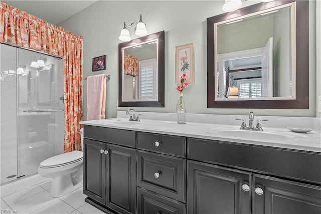 full bathroom featuring double vanity, toilet, a stall shower, and a sink