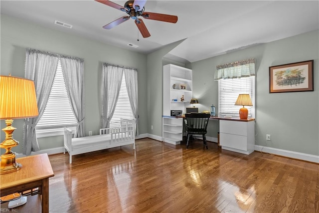 office area with baseboards, wood finished floors, visible vents, and a healthy amount of sunlight