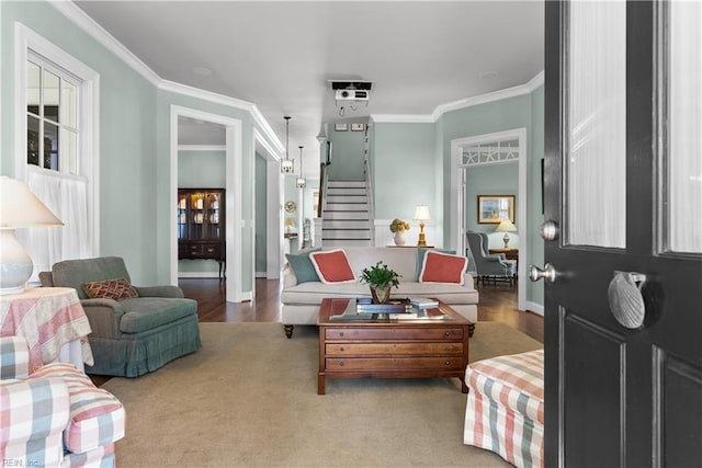 living room with wood finished floors, stairway, baseboards, and ornamental molding