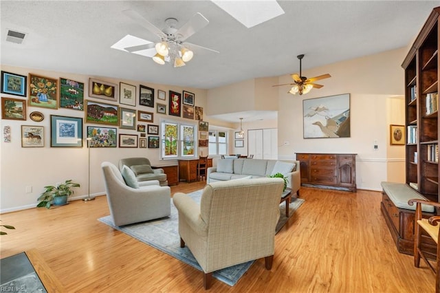 living area featuring visible vents, a skylight, and a ceiling fan