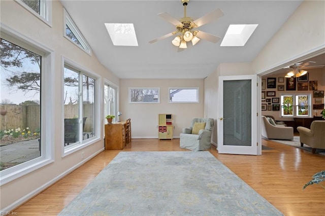 living area featuring ceiling fan, baseboards, wood finished floors, and a skylight