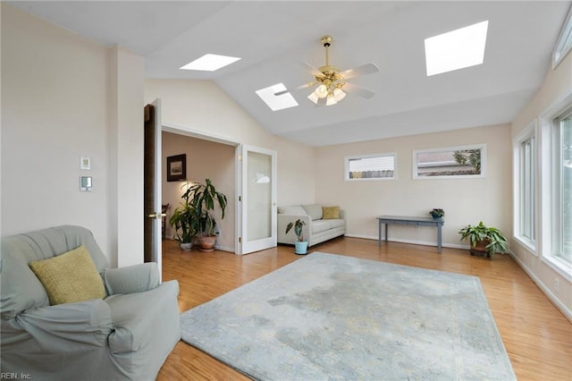 sitting room featuring vaulted ceiling with skylight, a healthy amount of sunlight, ceiling fan, and light wood finished floors