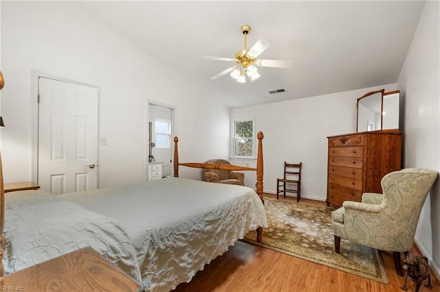 bedroom with vaulted ceiling, wood finished floors, visible vents, and ceiling fan