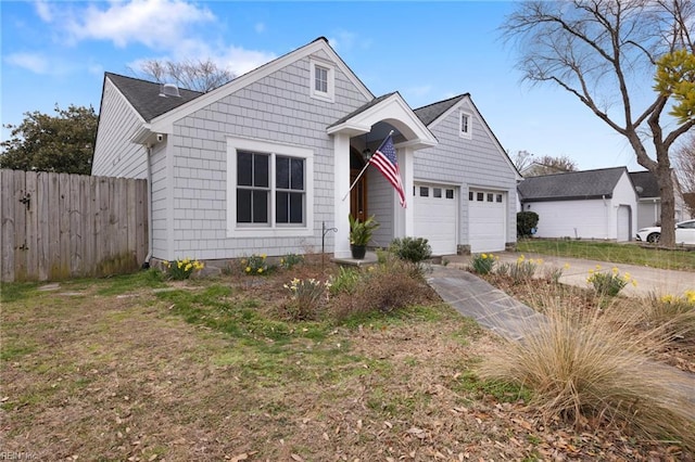 view of front of house featuring a garage, concrete driveway, and fence