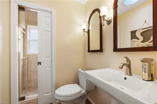 bathroom with a sink, tiled shower, and toilet