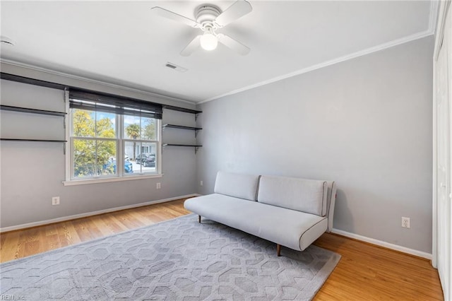 living area featuring visible vents, baseboards, ornamental molding, wood finished floors, and a ceiling fan