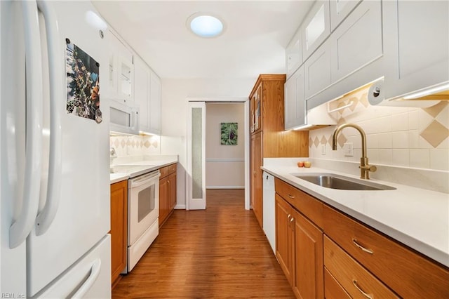 kitchen featuring white appliances, wood finished floors, a sink, light countertops, and backsplash