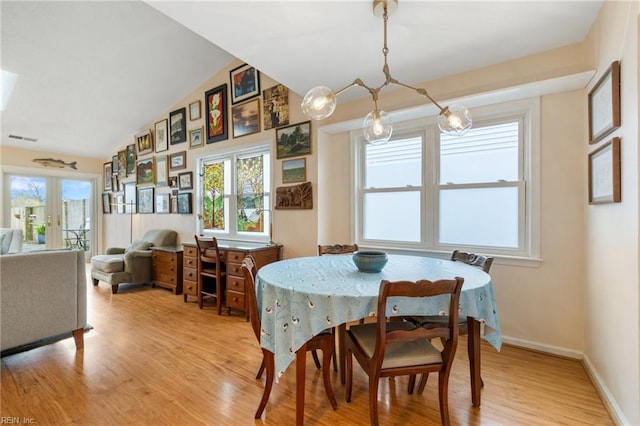 dining room with light wood-type flooring, visible vents, a wealth of natural light, and vaulted ceiling