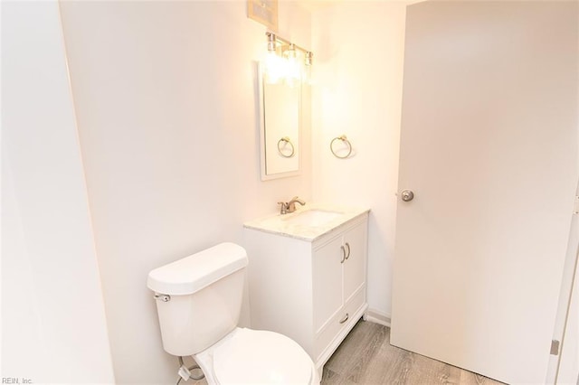 half bathroom featuring toilet, vanity, and wood finished floors