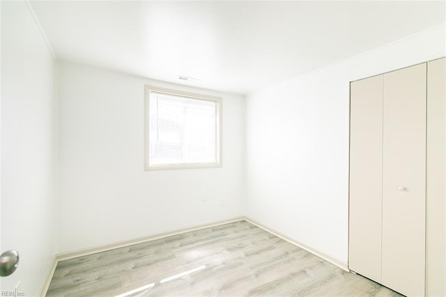 unfurnished bedroom with light wood finished floors and a closet