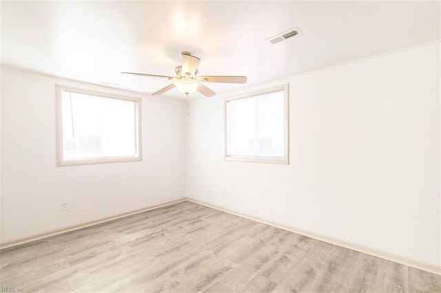 spare room with ceiling fan, visible vents, a wealth of natural light, and light wood-type flooring