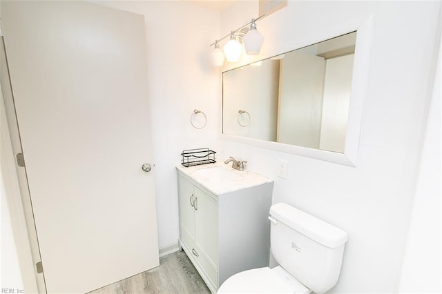 bathroom featuring toilet, vanity, and wood finished floors