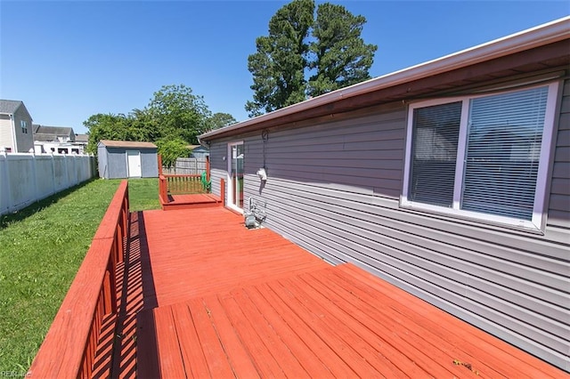 wooden terrace with a storage shed, a yard, fence, and an outbuilding