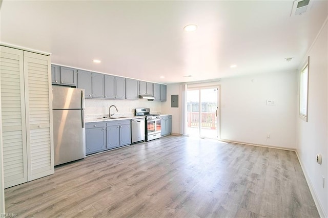 kitchen with a sink, stainless steel appliances, gray cabinets, and light countertops