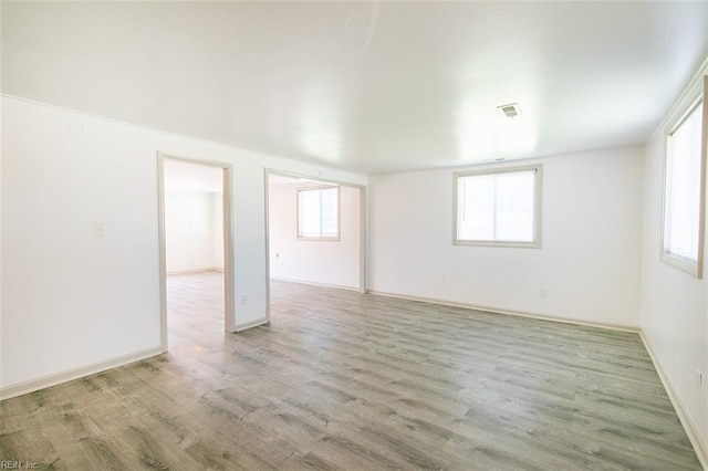 spare room with wood finished floors, visible vents, and baseboards