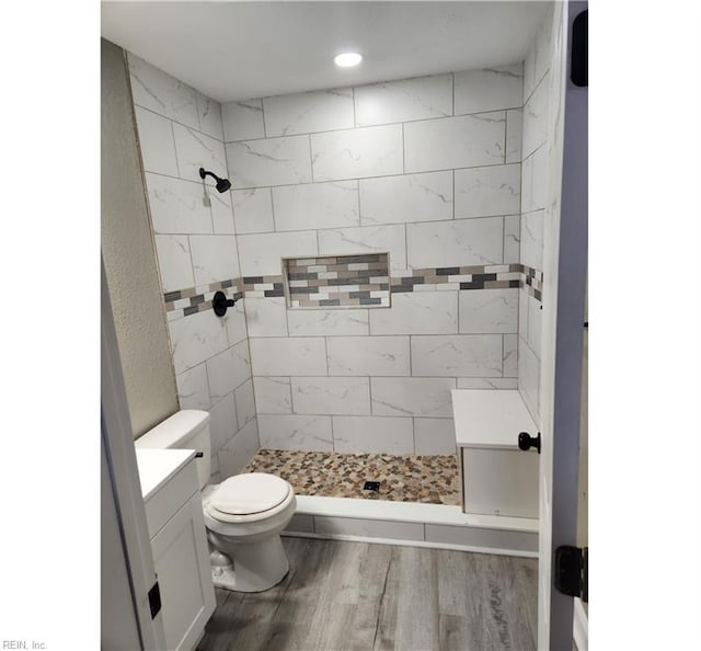 bathroom featuring vanity, toilet, wood finished floors, and a shower stall