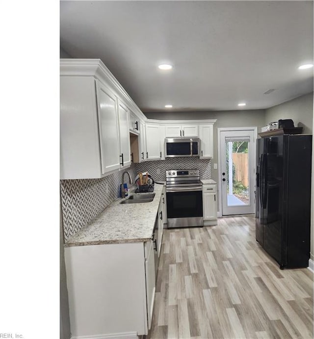 kitchen with tasteful backsplash, light wood-style flooring, stainless steel appliances, white cabinetry, and a sink