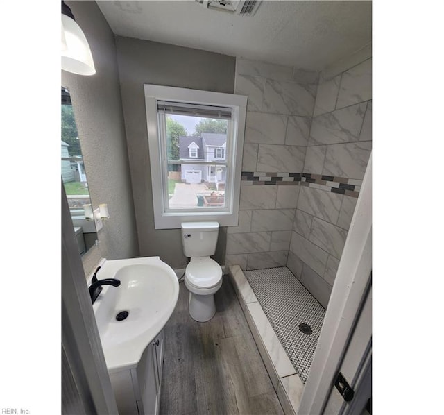 bathroom with visible vents, a shower stall, toilet, wood finished floors, and vanity