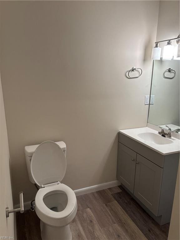 bathroom featuring toilet, vanity, baseboards, and wood finished floors