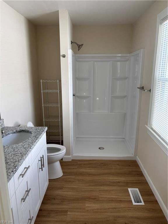 full bathroom with vanity, wood finished floors, visible vents, a walk in shower, and toilet