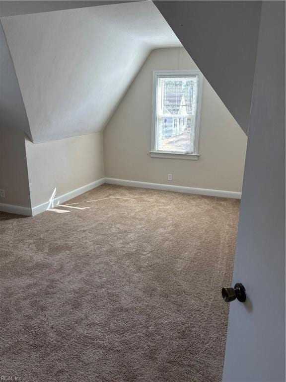 additional living space featuring baseboards, lofted ceiling, and carpet flooring