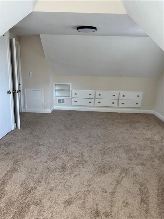 additional living space with visible vents, baseboards, carpet, and vaulted ceiling