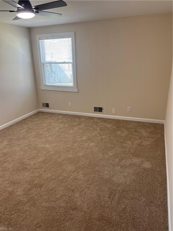 unfurnished room featuring visible vents, carpet floors, baseboards, and a ceiling fan