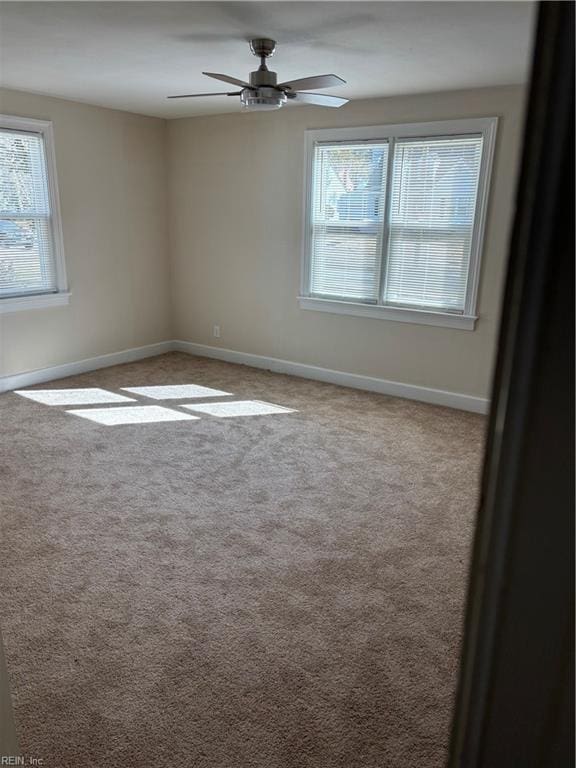 carpeted spare room featuring baseboards and ceiling fan