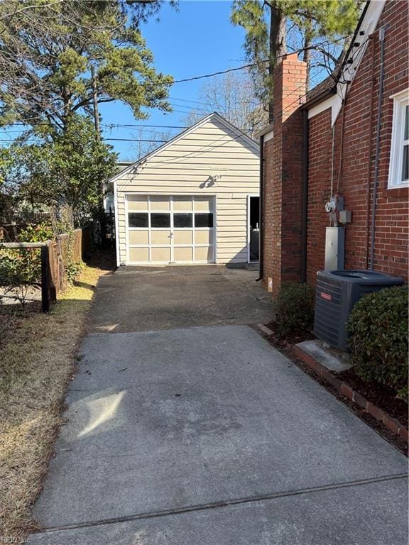 detached garage featuring aphalt driveway, cooling unit, and fence